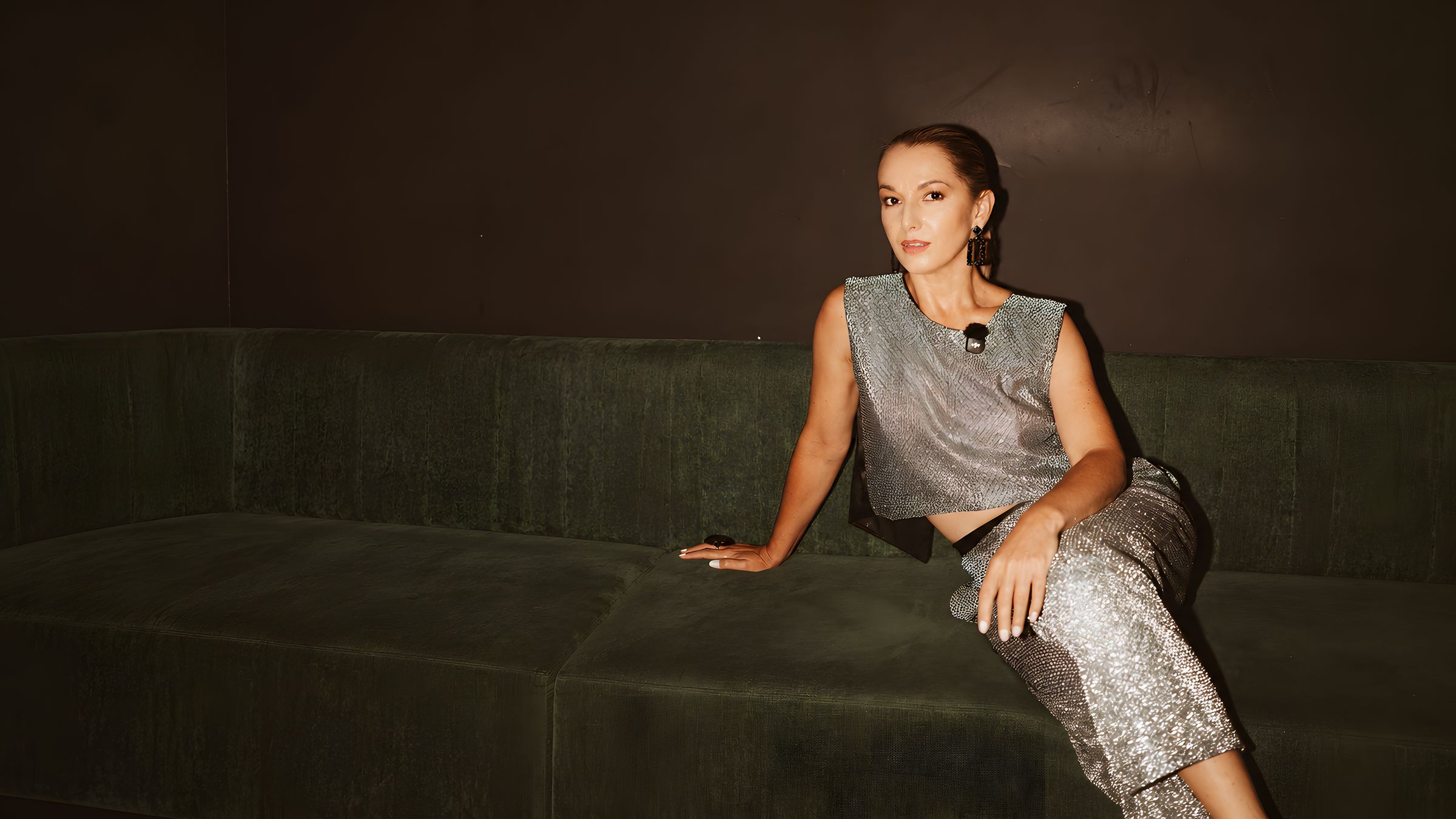 Nina Pimenta in a silver sequin set on a green velvet sofa